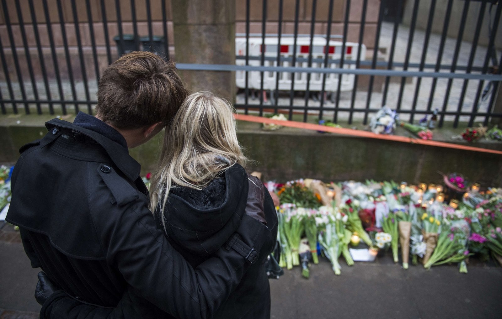 Una pareja toma un momento para reflexionar después de poner las flores para las víctimas del tiroteo fuera de la principal sinagoga en Copenhague, Dinamarca.