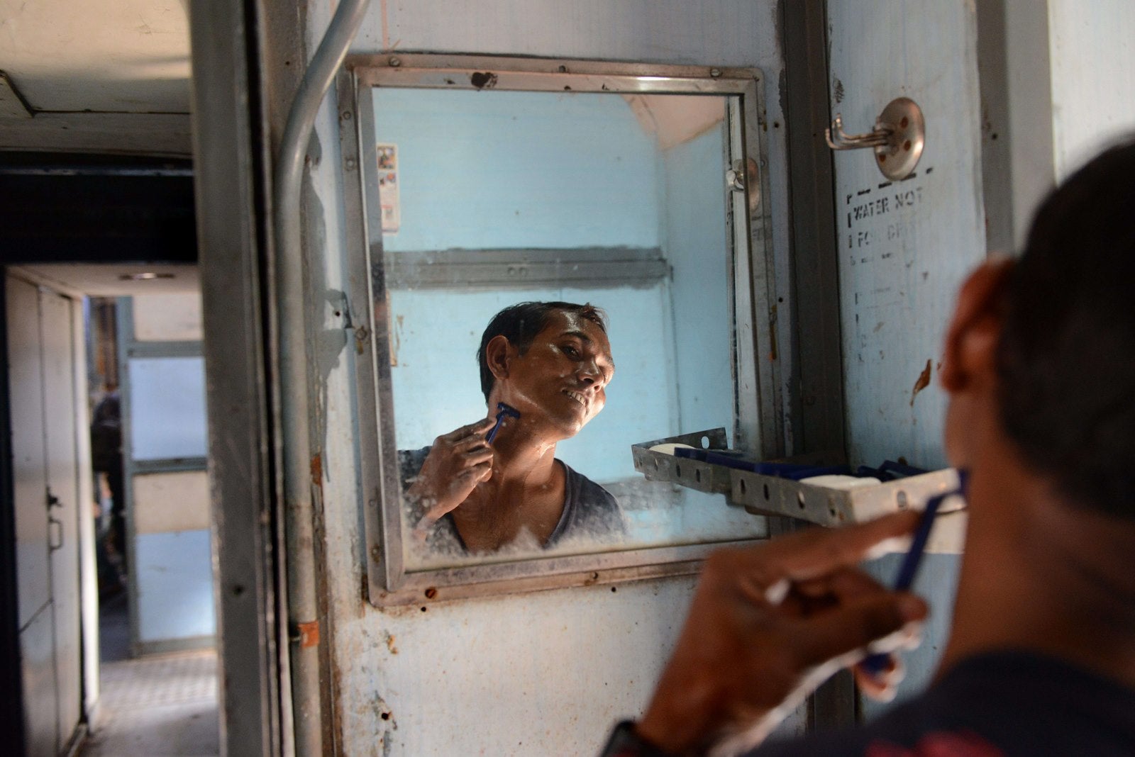 Un pescador indio se afeita en el tren mientras se llega a la estación en Ahmedabad.