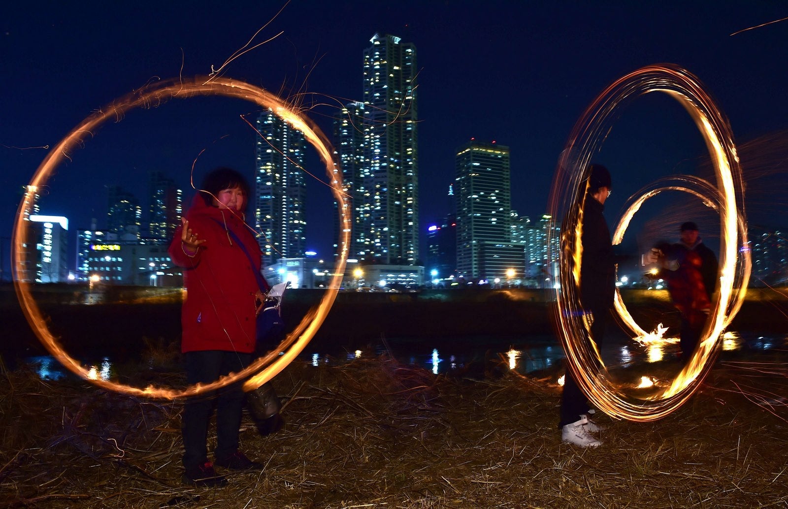 Surcoreanos hacen girar bolas de fuego para celebrar la próxima luna llena en un parque junto al río en Seúl.