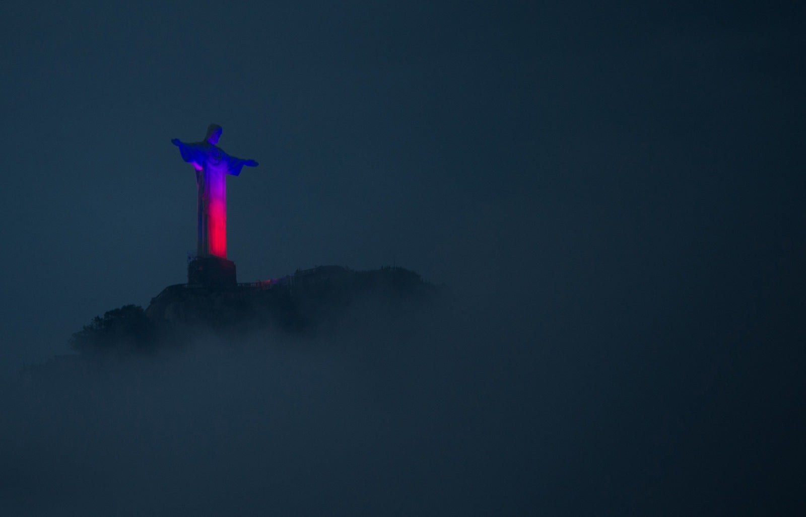 La estatua del Cristo Redentor, encima del monte Corcovado, se ilumina de rojo y azul, en Río de Janeiro