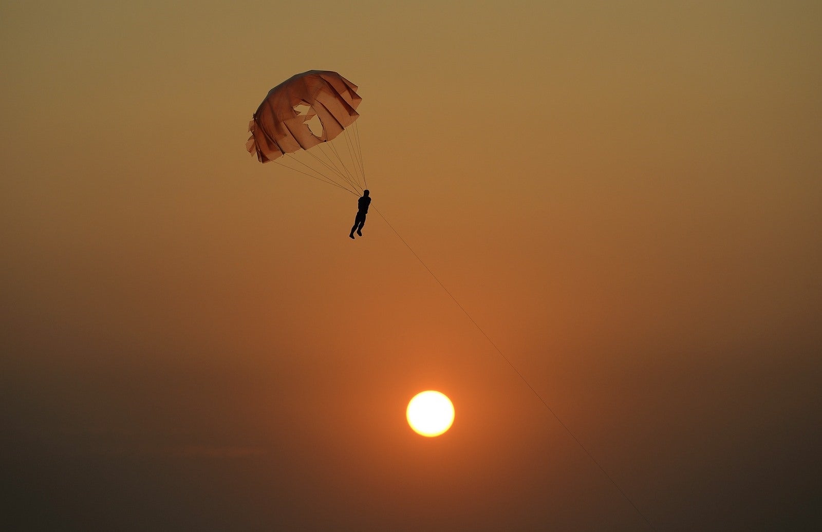 Un vendedor de la India (invisible) vuela un juguete paracaídas para atraer a los clientes en la playa Juhu, durante una puesta de sol en Mumbai