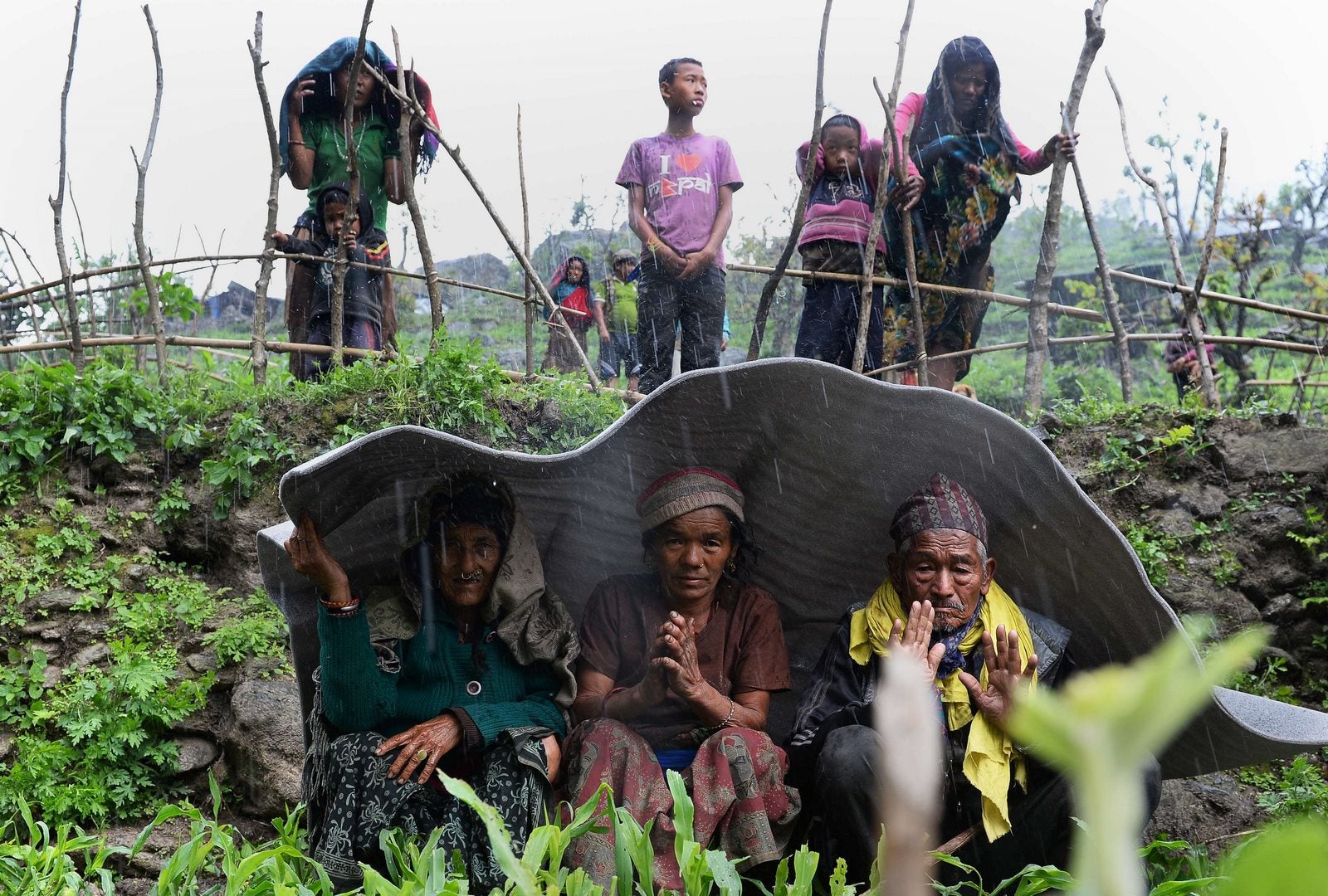 Aldeanos nepales se refugian de la lluvia durante las operaciones de socorro tras el terremoto en Lapu en Gorkha.