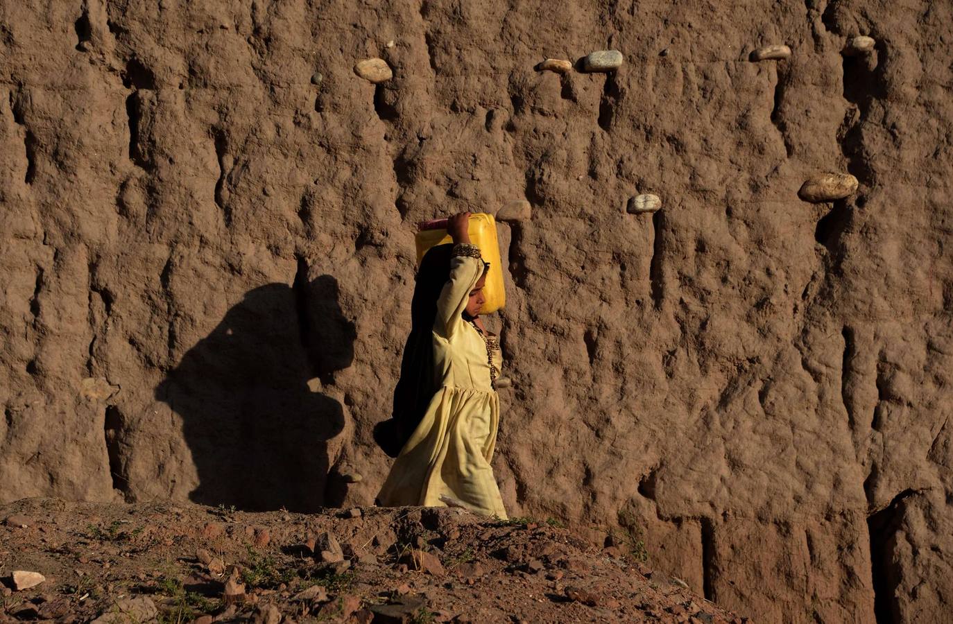 Una niña afgana lleva una lata de agua en el hombro en Jalalabad el 31 de mayo de 2015. La pobreza y la insurgencia en curso por el Talibán derrocado aún representa una amenaza para la estabilidad del país.