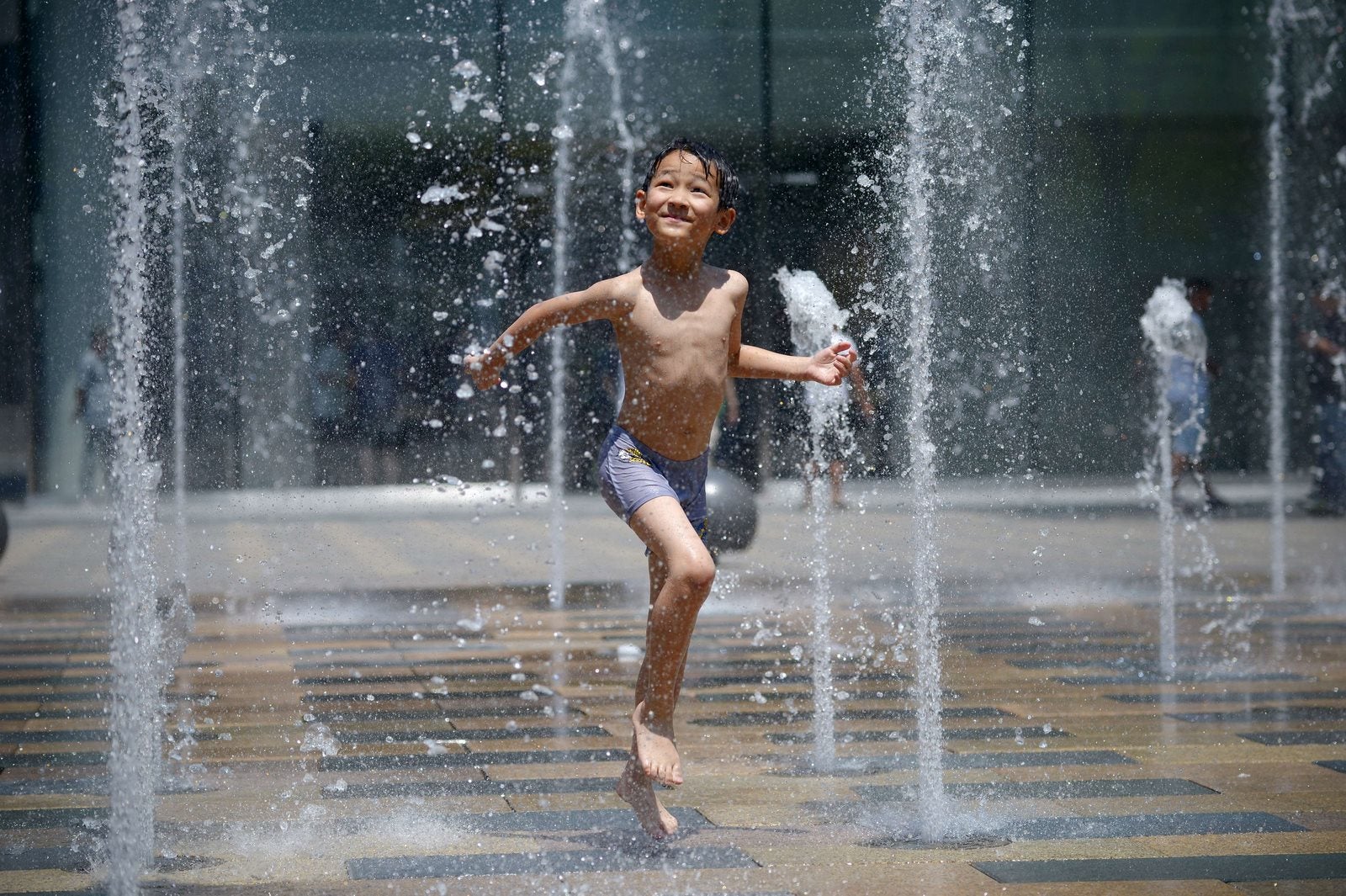 Un niño juega en una fuente cerca de un centro comercial en Pekin .