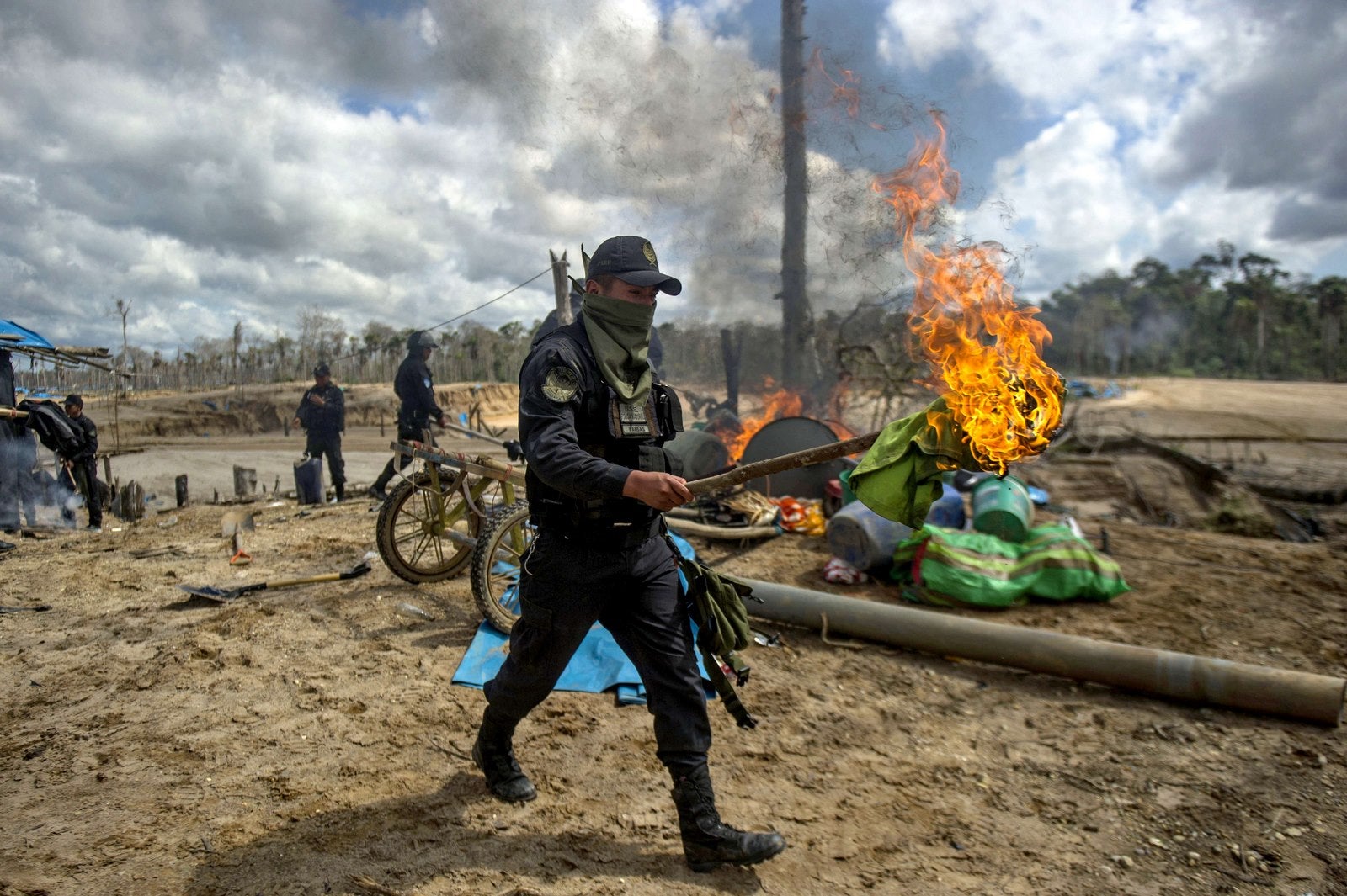 Un policía sostiene una antorcha encendida durante una operación en el área de la minería ilegal de oro de La Pampa, en Madre de Dios, selva sur del Perú, donde 60.000 hectáreas de bosques han sido destruidas por esta actividad.