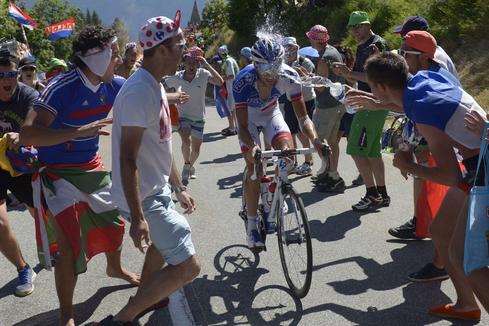 Aficionados franceses rocian con agua a Thibaut Pinot escapado del pelotón en una etapa del Tour de Francia.