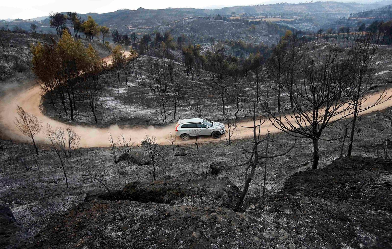 Un coche circula por un camino de tierra en la zona del incendio de Montserrat en Sant Salvador de Guardiola, en la región nororiental de Cataluña.