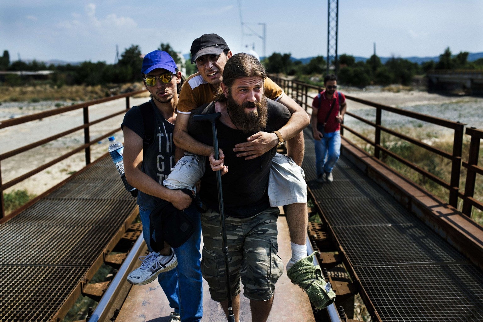 Inmigrantes sirios llevan a su amigo herido,  sobre las vías del ferrocarril hacia la ciudad de Gevgelija en la frontera entre Macedonia griega.