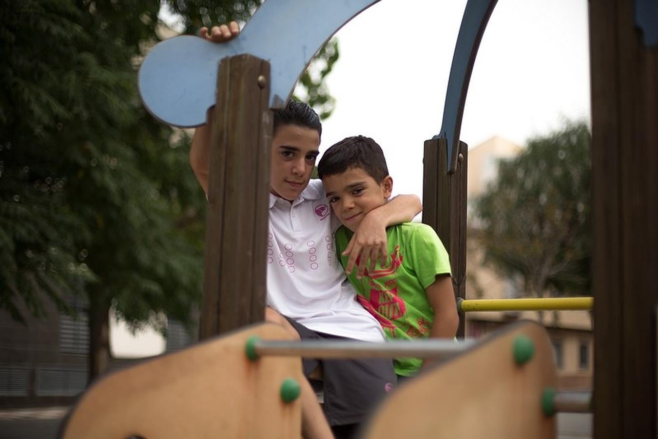 Miguel Ángel y David, abrazados sobre un columpio del parque.