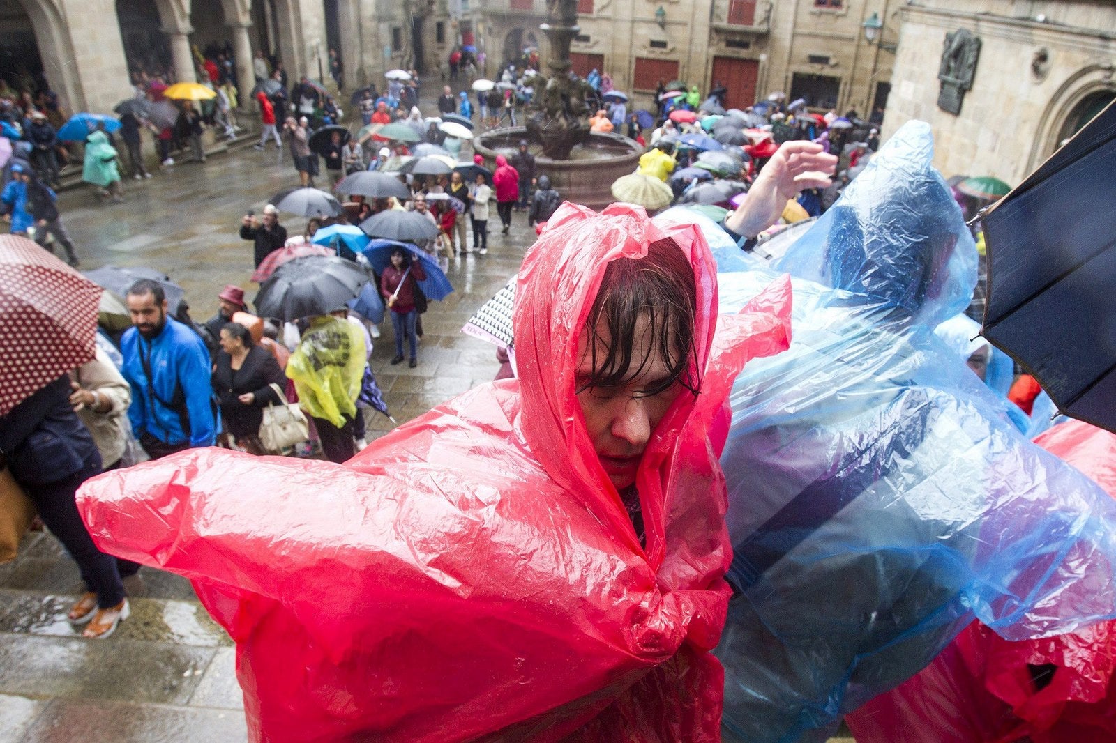 Decenas de turistas hacen cola en uno de los accesos a la Catedral de Santiago pertrechados con plásticos y paraguas para protegerse de la lluvia. Las tormentas y lluvias han tomado Galicia en este penúltimo fin de semana de agosto, con temporal costero en el litoral del noroeste de A Coruña y en la zona de la Mariña de Lugo