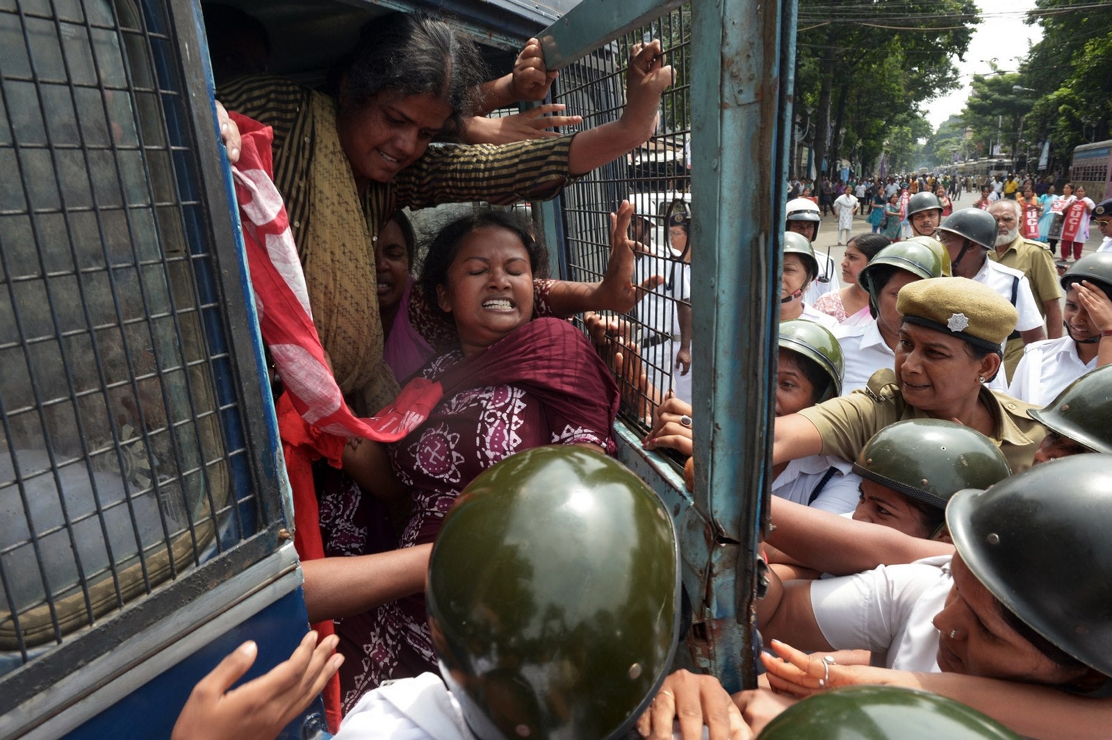 La policía india tratan de cerrar la puerta de una camioneta de la policía como activistas sindicales detenidos intentan abrirla durante una protesta en Calcuta.