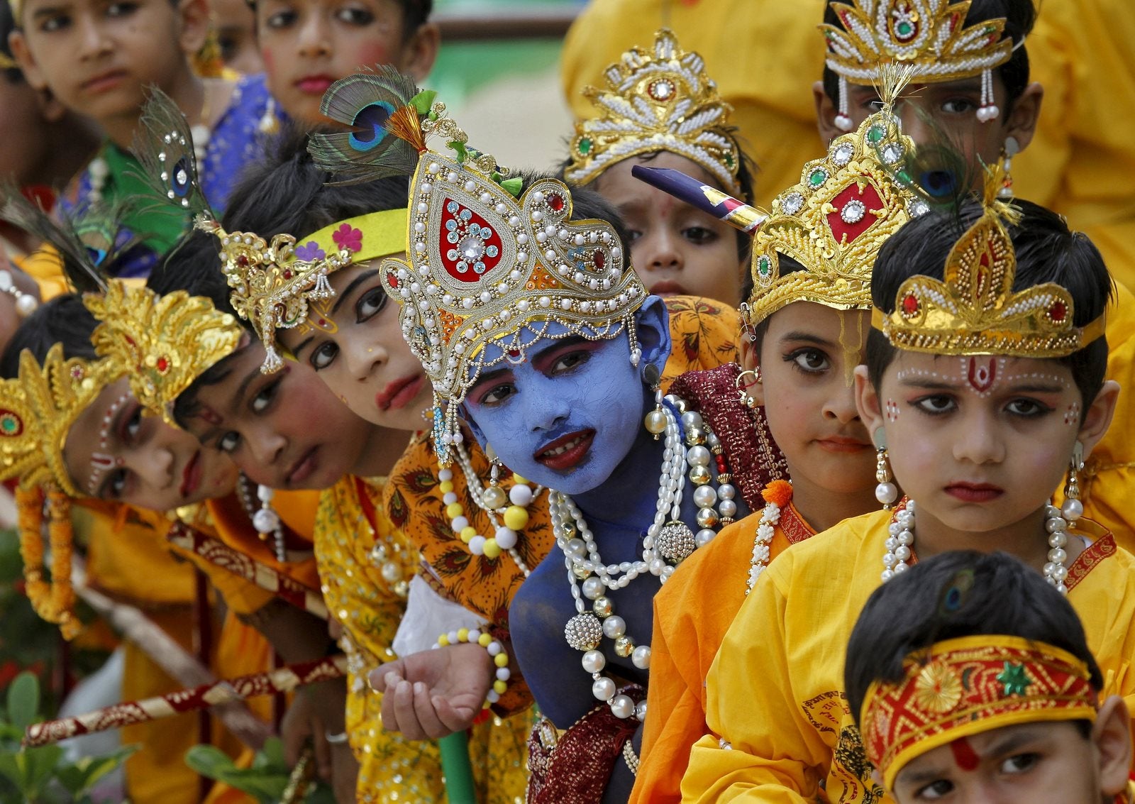 Escolares disfrazados de señor hindú Krishna esperan durante las celebraciones de la víspera de la fiesta Janmashtami en Chandigarh, India.