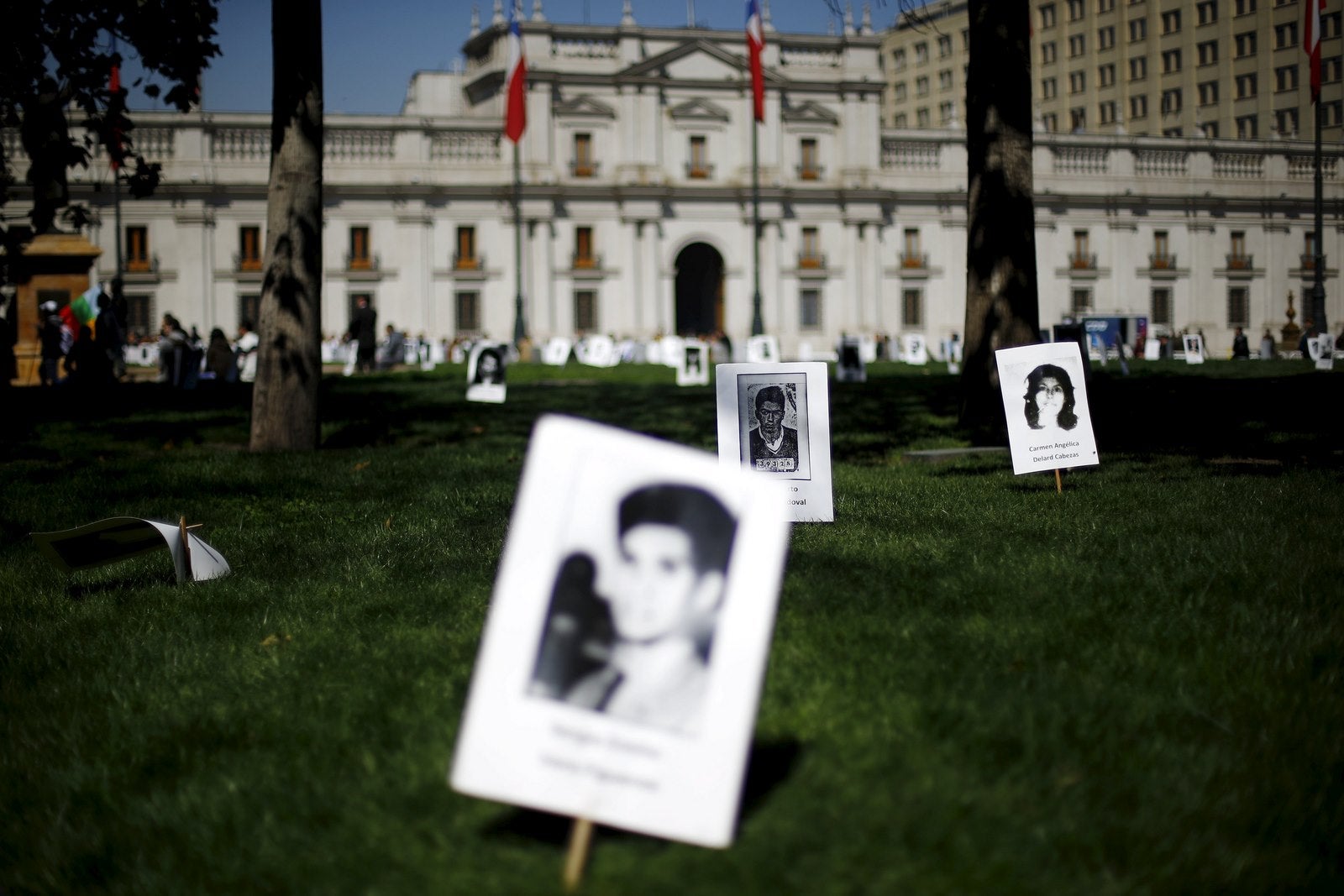 Imágenes de las víctimas de abusos contra los derechos humanos durante el gobierno del ex dictador Augusto Pinochet se colocan delante de la "La Moneda" Palacio Presidencial durante una manifestación en Santiago.