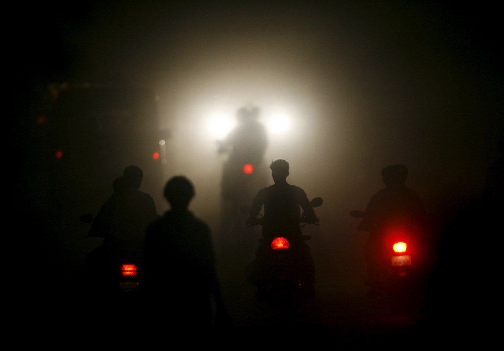 Motociclistas a través de la niebla en una carretera en la ciudad industrial de Vapi, a unos 180 km (112 millas) al norte de Mumbai.