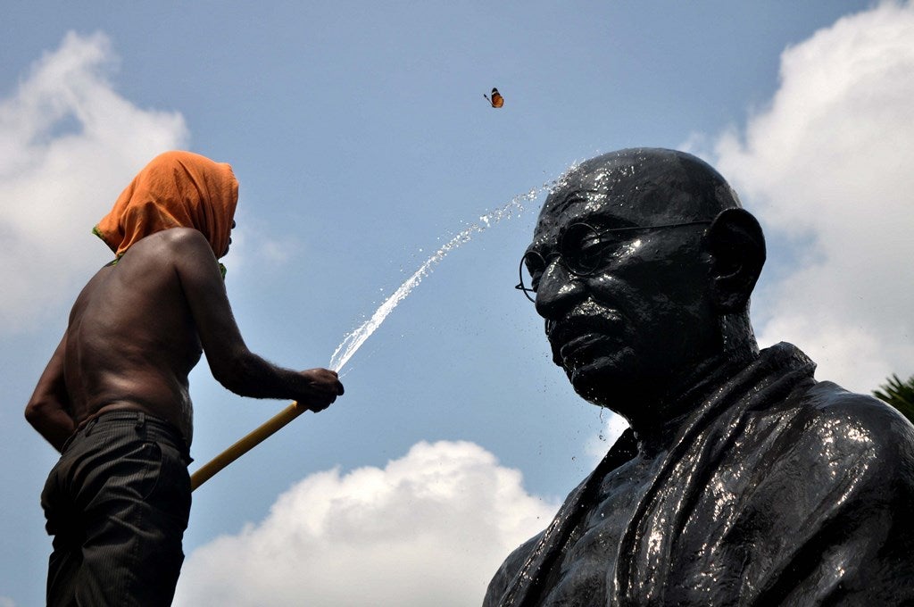 Mariposas vuelan alrrededor de una estatua de Mahatma Gandhi, mientras un trabajador la limpia  en la víspera de Gandhi Jayanti en Gandhi Park, en la ciudad oriental Bhubenaswar.