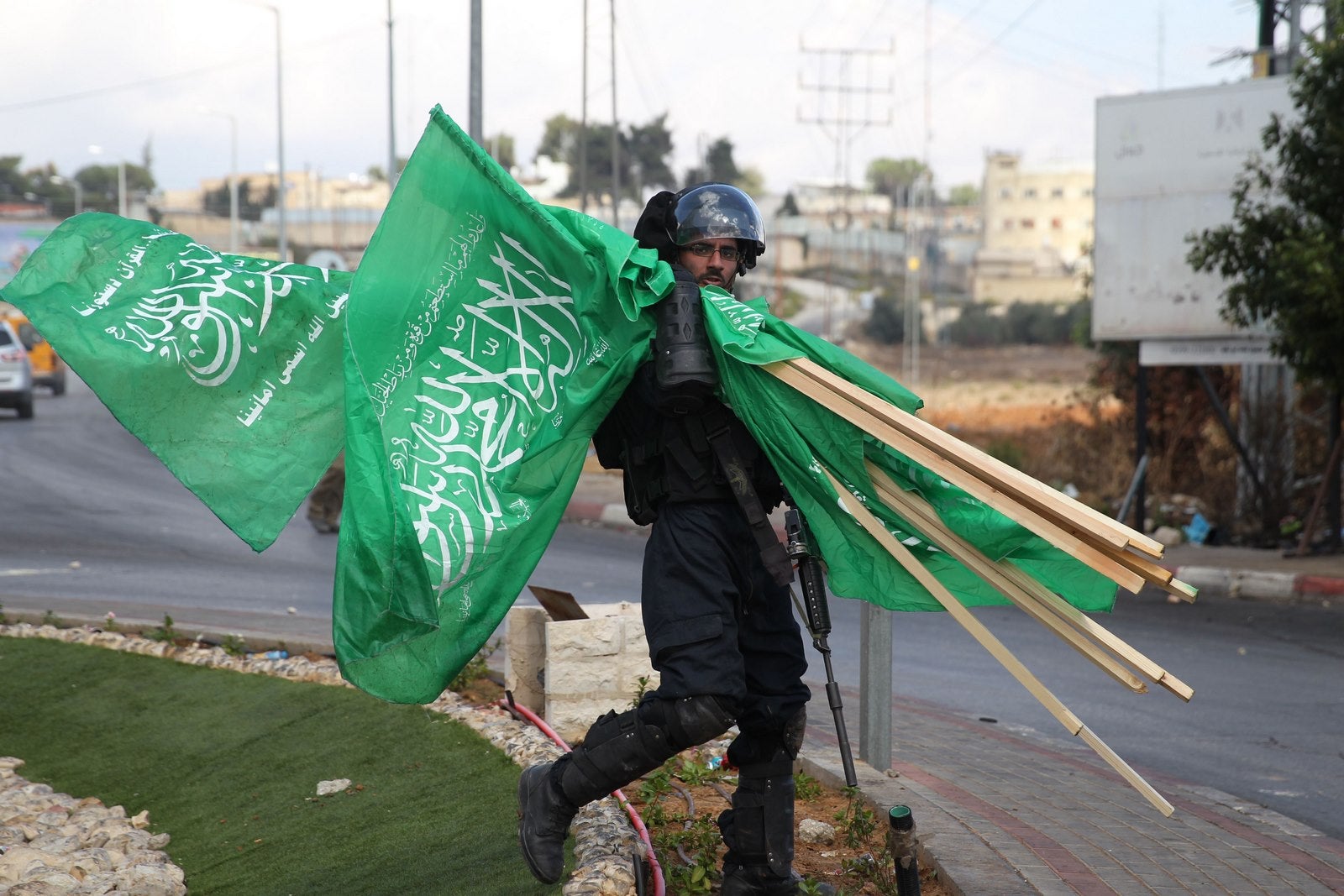 Un miembro de las fuerzas de seguridad israelíes lleva banderas del movimiento islamista palestino Hamas que se apoderó durante los enfrentamientos con manifestantes palestinos en Beit El, cerca de la ciudad cisjordana de Ramala.