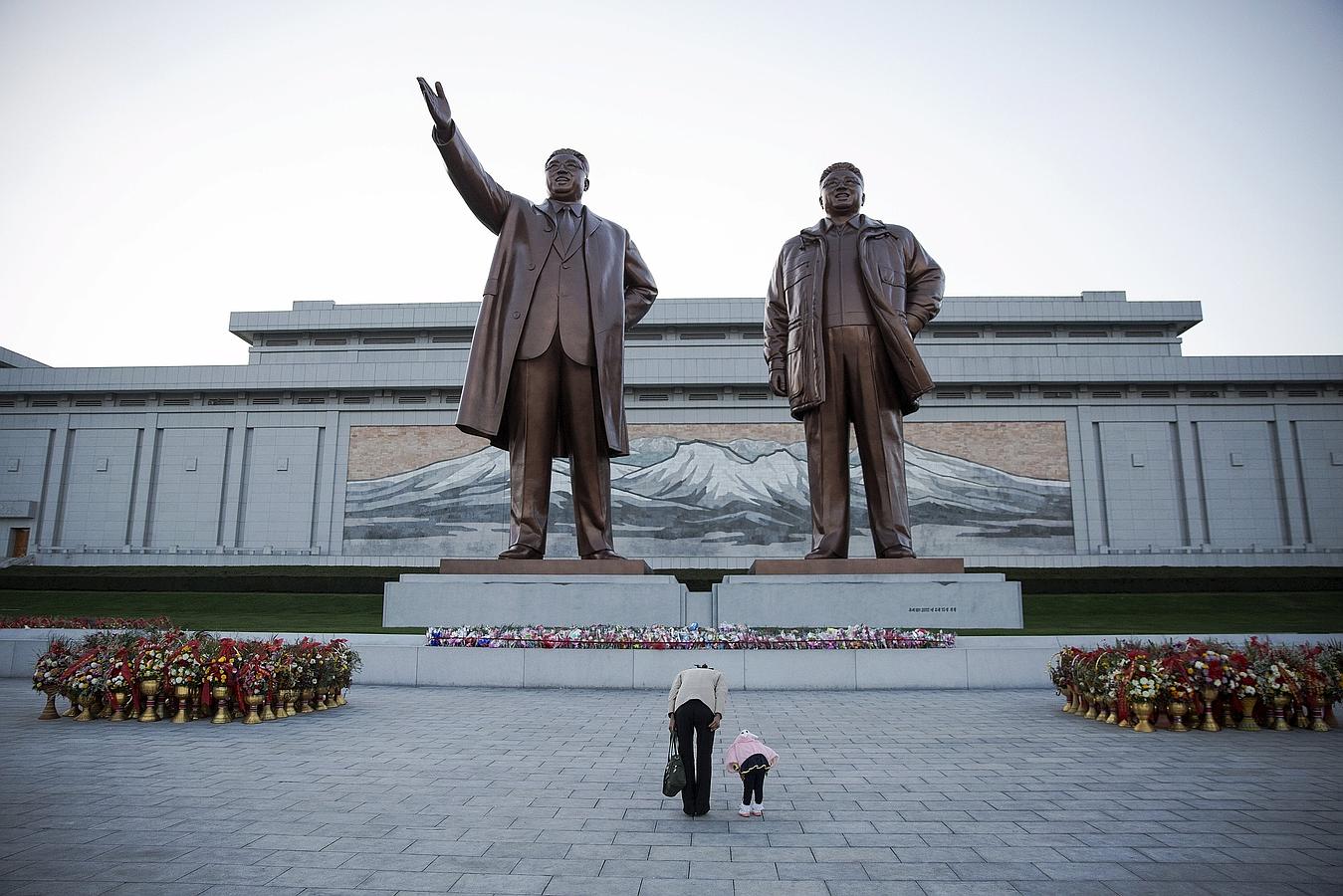Una mujer y su hija muestram sus respetos a las estatuas del fundador de Corea del Norte Kim Il Sung (L) y el difunto líder Kim Jong Il en Pyongyang.
