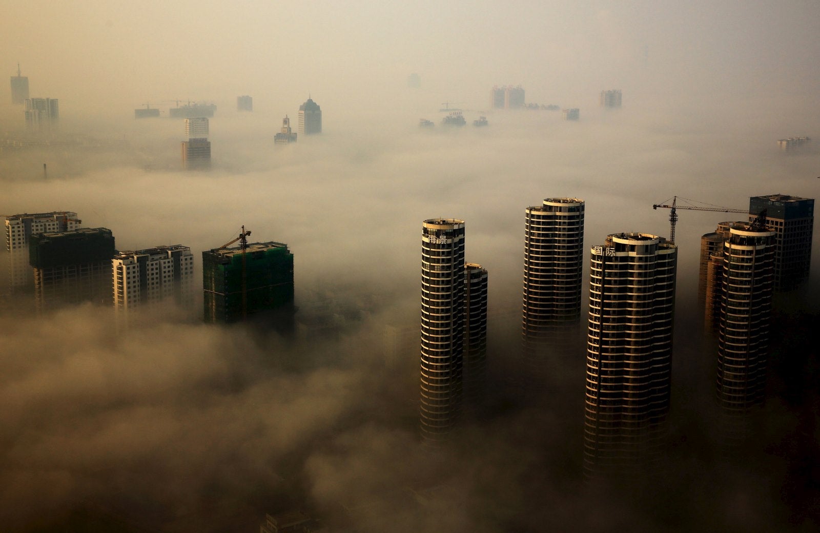 Edificios en construcción se ven entre la niebla en un día brumoso en Rizhao, provincia de Shandong, China.