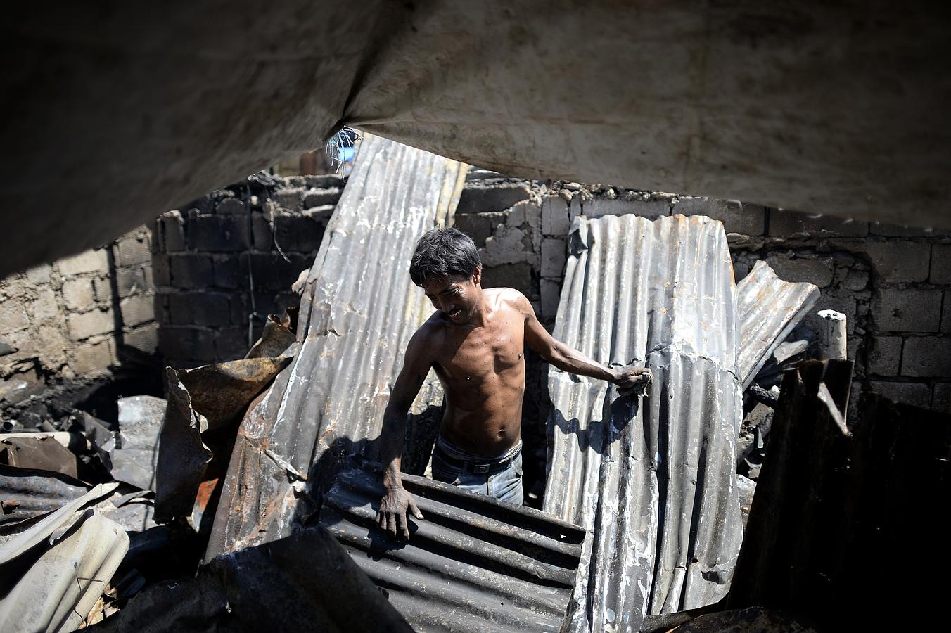 Un hombre entre los materiales de su casa destruida después de un incendio durante la noche que arraso un área de tugurios en Manila. El incendio destruyó 100 casas, dejando a 300 familias sin hogar.