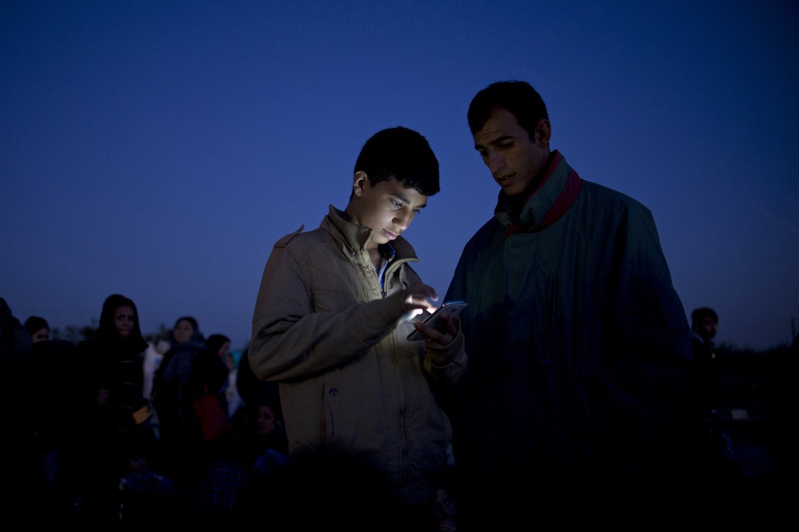 Un niño mira su teléfono mientras espera entrar en un campo de registro, después de cruzar la frontera entre Grecia y Macedonia, cerca de Gevgelija.