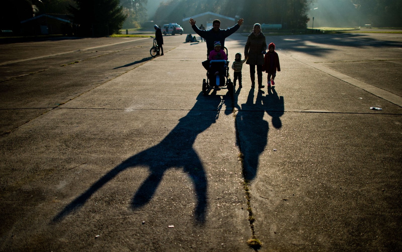 Miembros de una familia de refugiados de Siria proyectar sombras largas, al caminar sobre los terrenos del antiguo cuartel militar que sirven ahora como refugio para los solicitantes de asilo.
