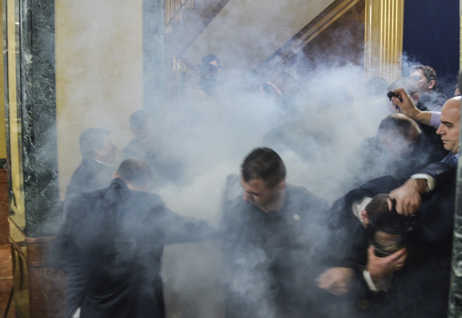 Miembros del Parlamento dejan el hemiciclo después de gases lacrimógenos lanzados por legisladores de la oposición, en el Parlamento de Kosovo en Pristina.