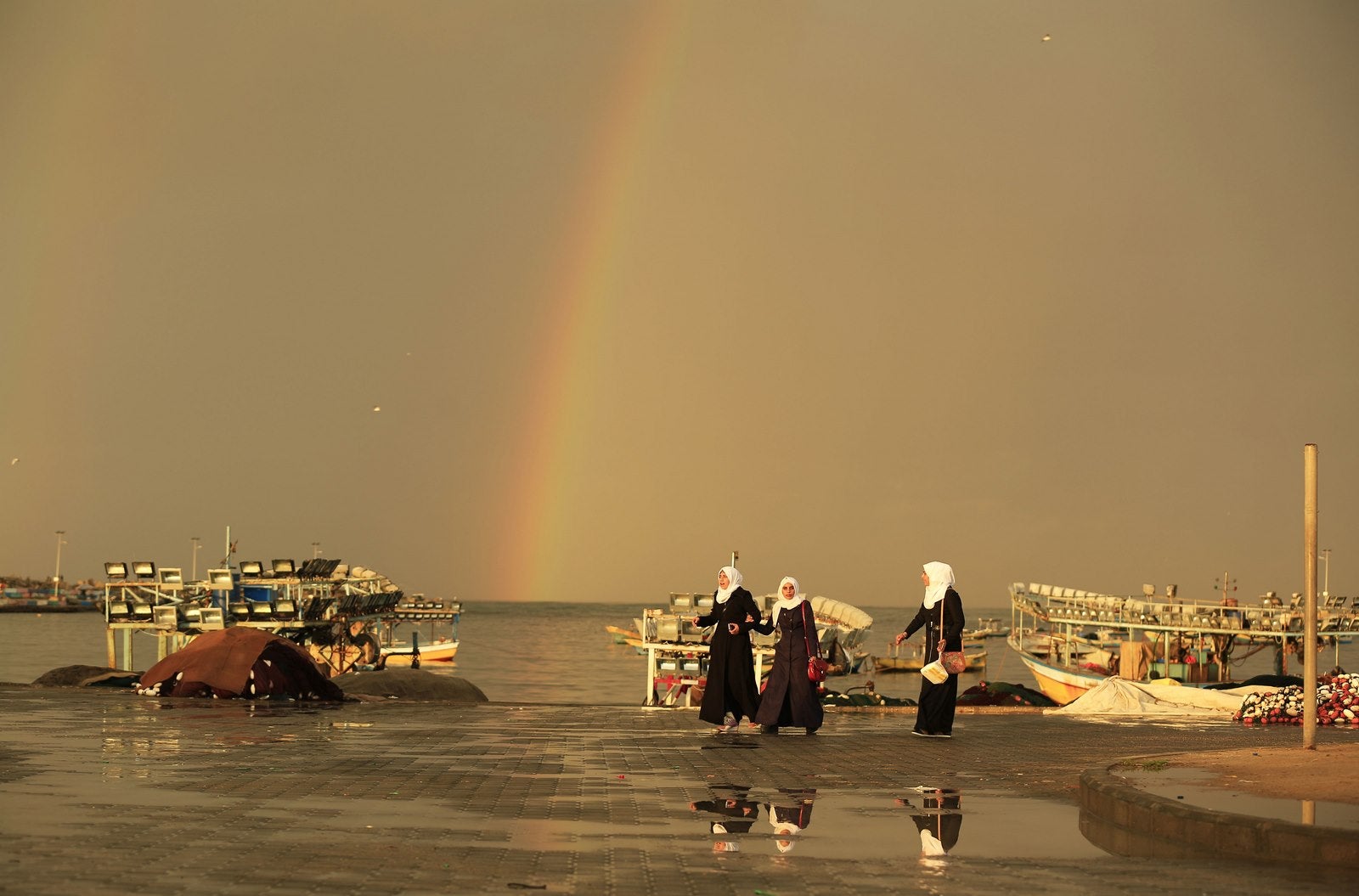 Escolares palestinos caminan delante de un arco iris que ilumina el cielo sobre la ciudad de Gaza.