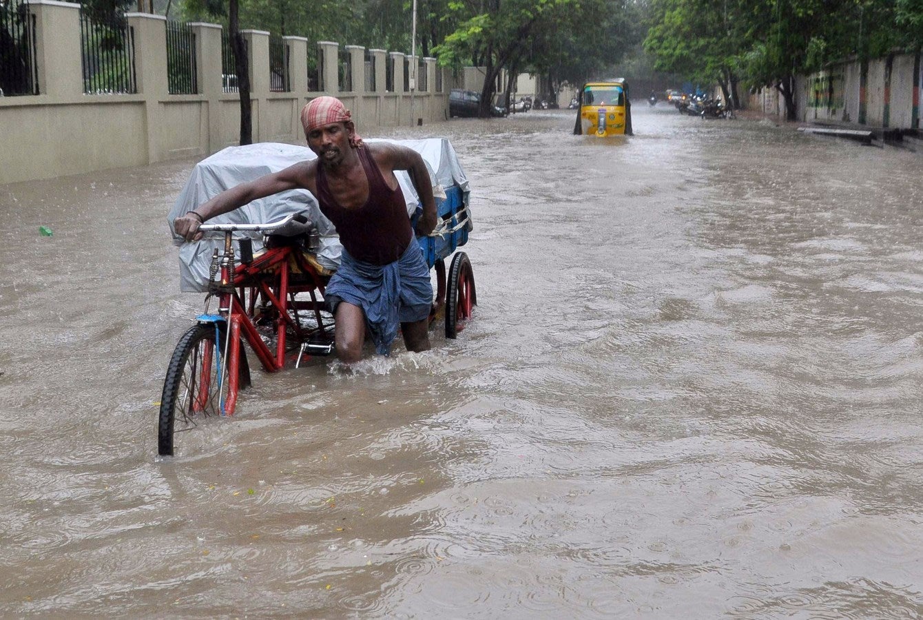 Un trabajador indio empuja su trishaw  por las alles inundadas en Chennai, sur de India.
