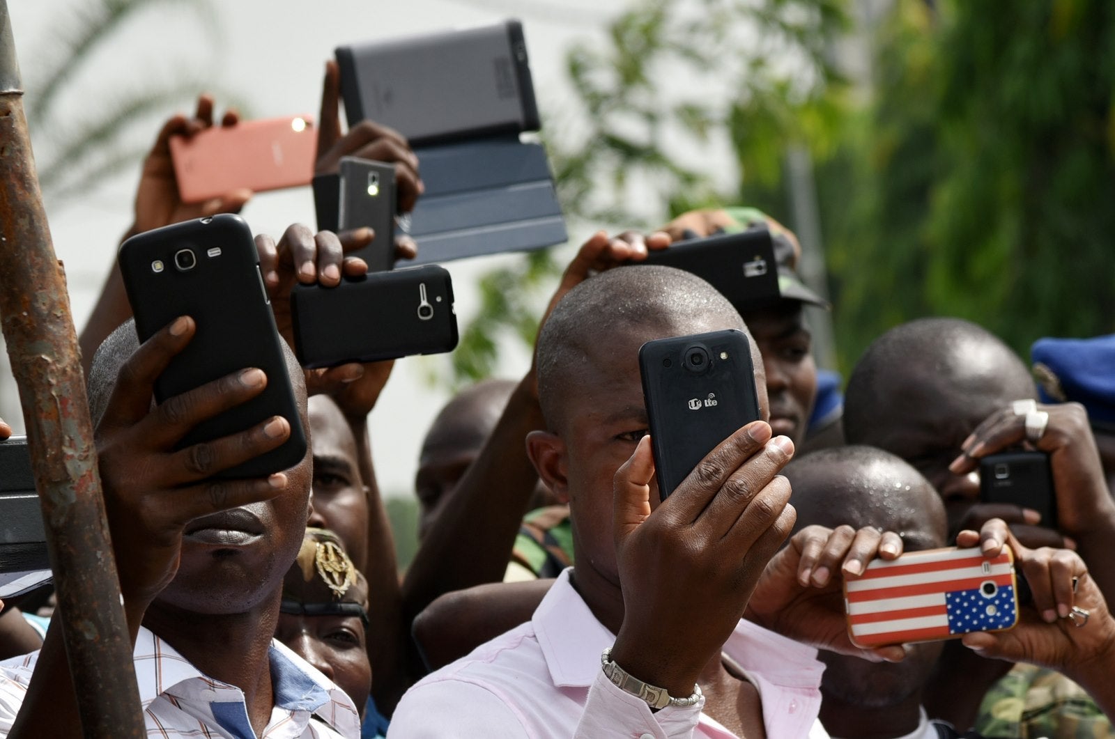 Familiares y amigos utilizan sus teléfonos móviles para filmar y tomar fotos de una ceremonia para rendir homenaje a los soldados de Costa de Marfil que fueron asesinados.