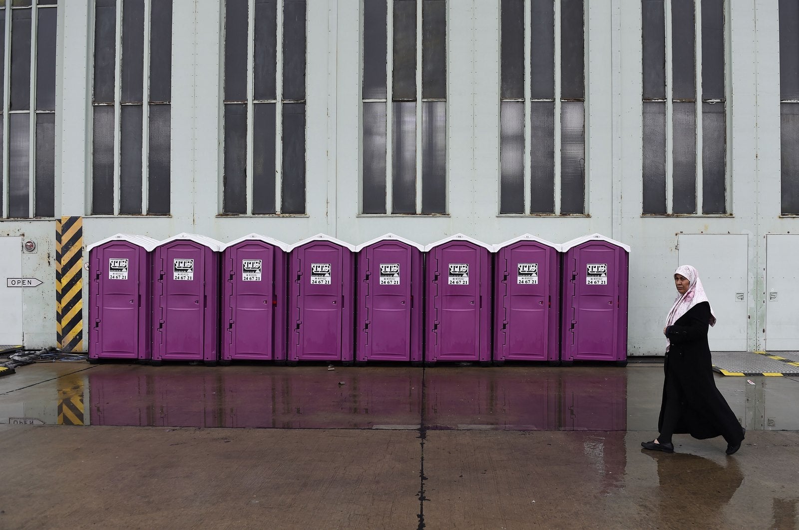 Una mujer camina delante de baños móviles fuera del alojamiento de refugiados en el antiguo aeropuerto de Tempelhof en Berlín.