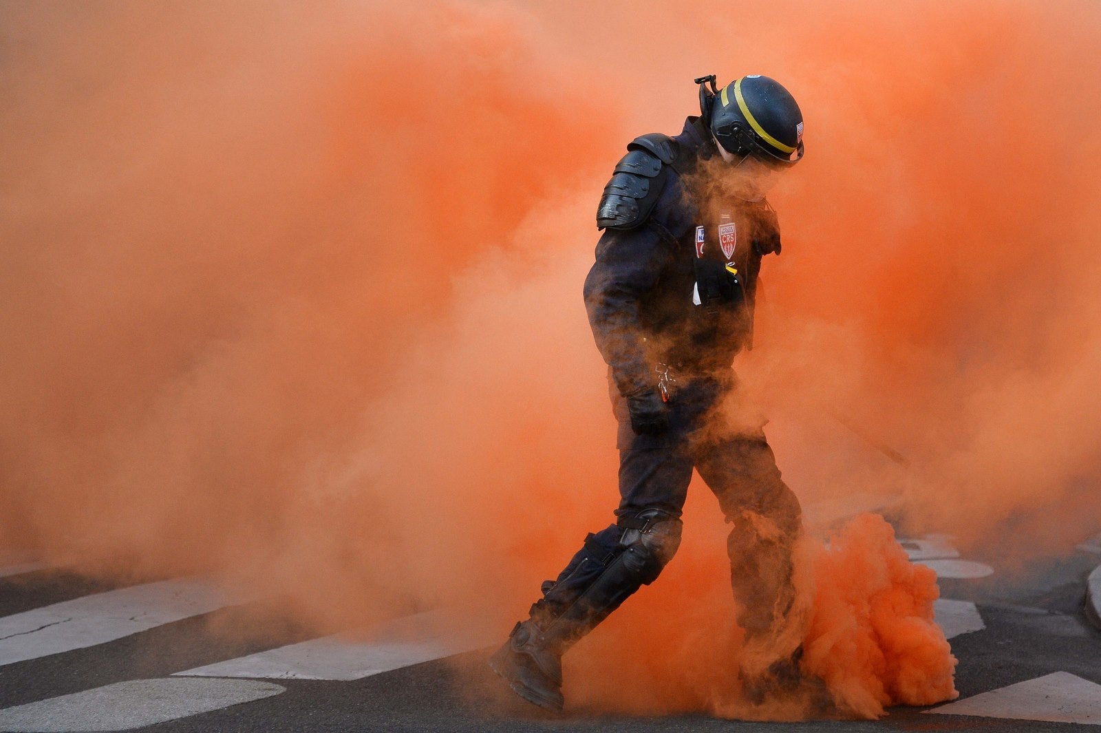Un policía antidisturbios camina a través del humo naranja de un gas lacrimógeno, en el oeste de Francia, durante una manifestación de activistas contra el estado de emergencia y el estado policial.