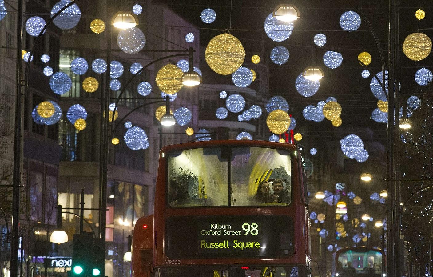 Autobuses de  Londres pasan por debajo de las luces de Navidad en Oxford Street, en el centro de Londres.