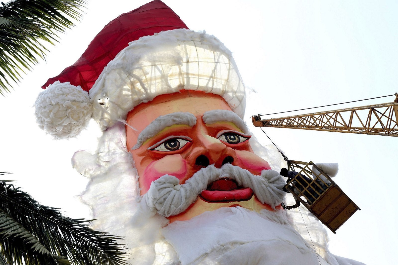Varios Trabajadores indios USAN Una grúa parra erigir un gigantesco Papá Noel Frente para la iglesia de San José con Motivo del Próximo Festival de Navidad Celebrado en Bangalore (India).