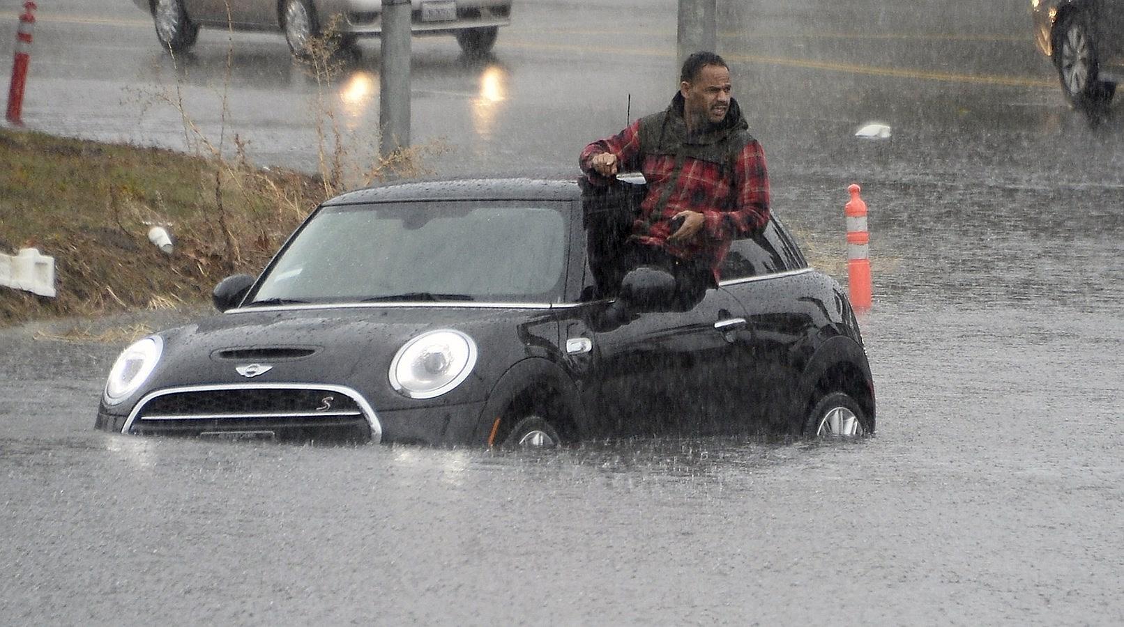 Un conductor sale por una ventana de su coche después de conducir por un camino inundado en Van Nuys, California.