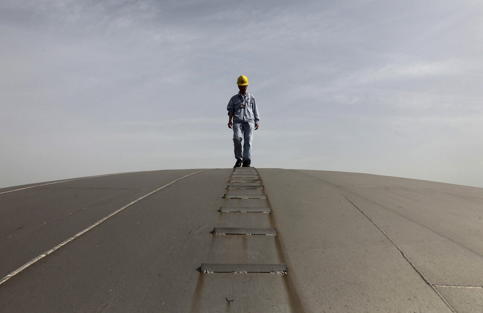 Un empleado camina en la parte superior de un tanque de petróleo en una refinería de Sinopec en Wuhan, provincia de Hubei, China.