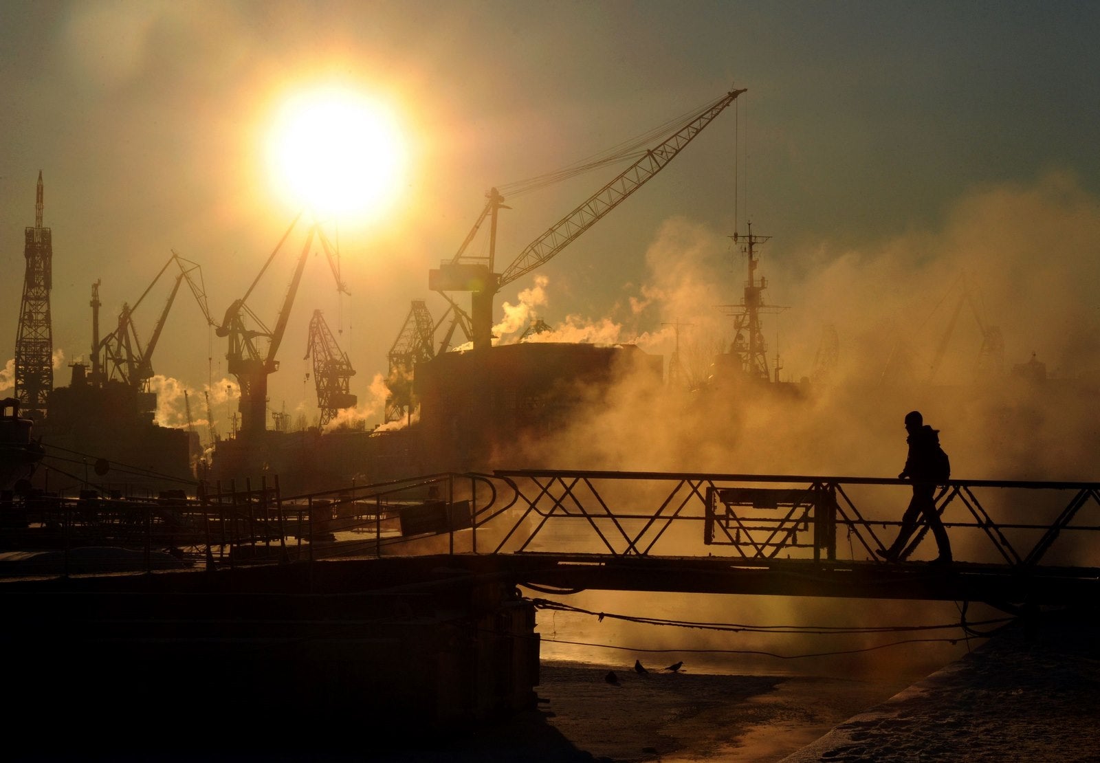 Un hombre cruza un puente en la orilla del río Neva en San Petersburgo.