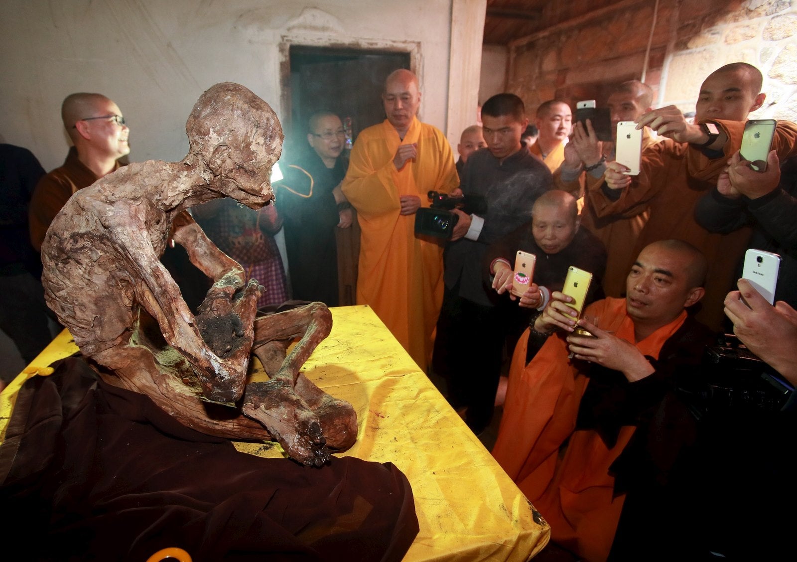 Monjes toman fotos con sus teléfonos móviles del cuerpo momificado de un monje en el templo Puzhao en Quanzhou, provincia de Fujian, China.