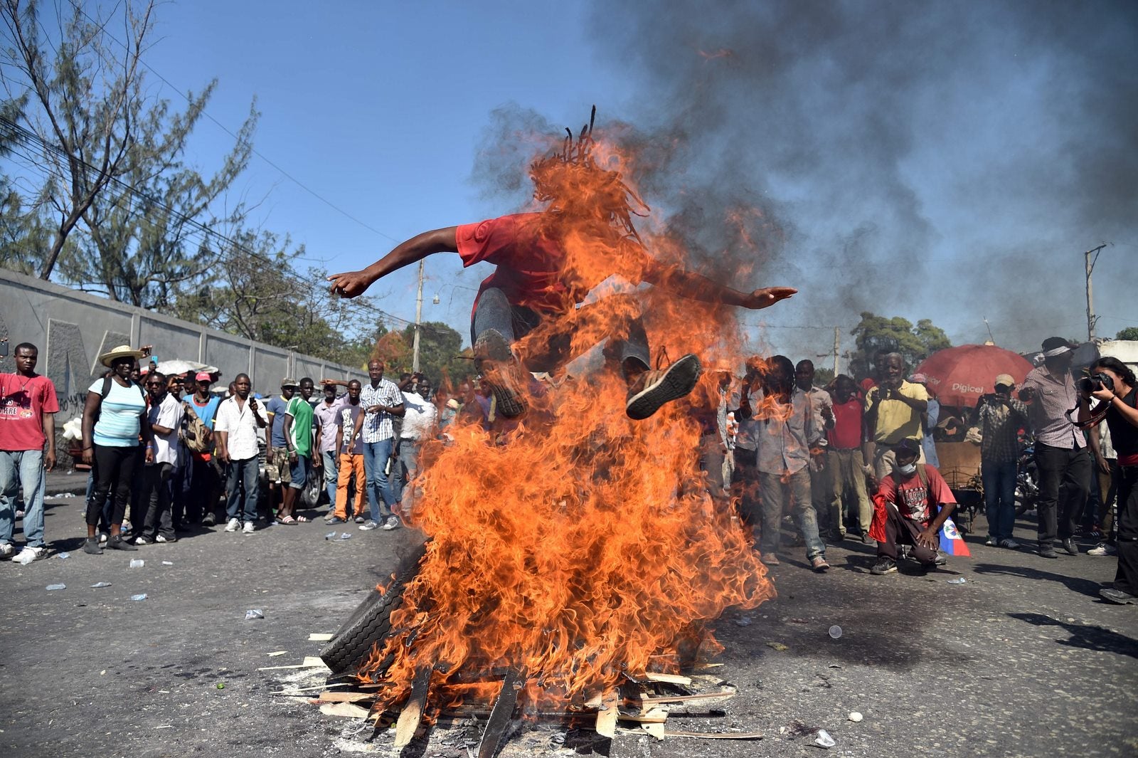 Un hombre salta sobre el fuego, mientras que llevar a cabo una ceremonia de vudú antes de una protesta por las calles de Puerto Príncipe.