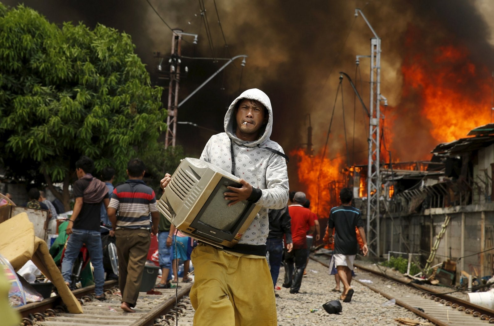 Un hombre lleva un televisor lejos de un incendio en un barrio pobre al lado de las vías del ferrocarril en Kampung Bandan, el norte de Yakarta, Indonesia.