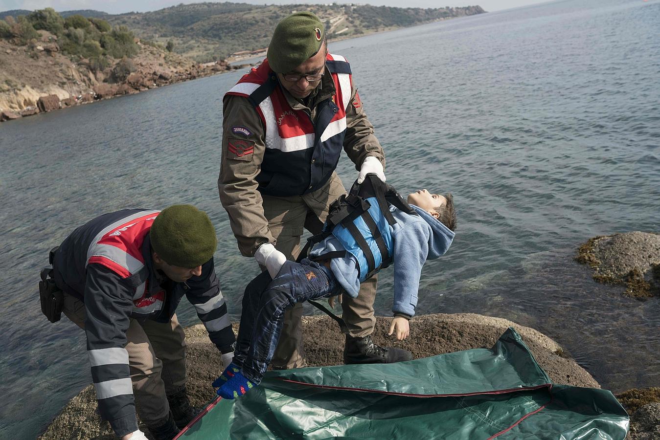 Gendarmes turcos ponen el cuerpo de un niño ahogado en una bolsa para cadáveres en una playa en el distrito de Canakkale Bademli.