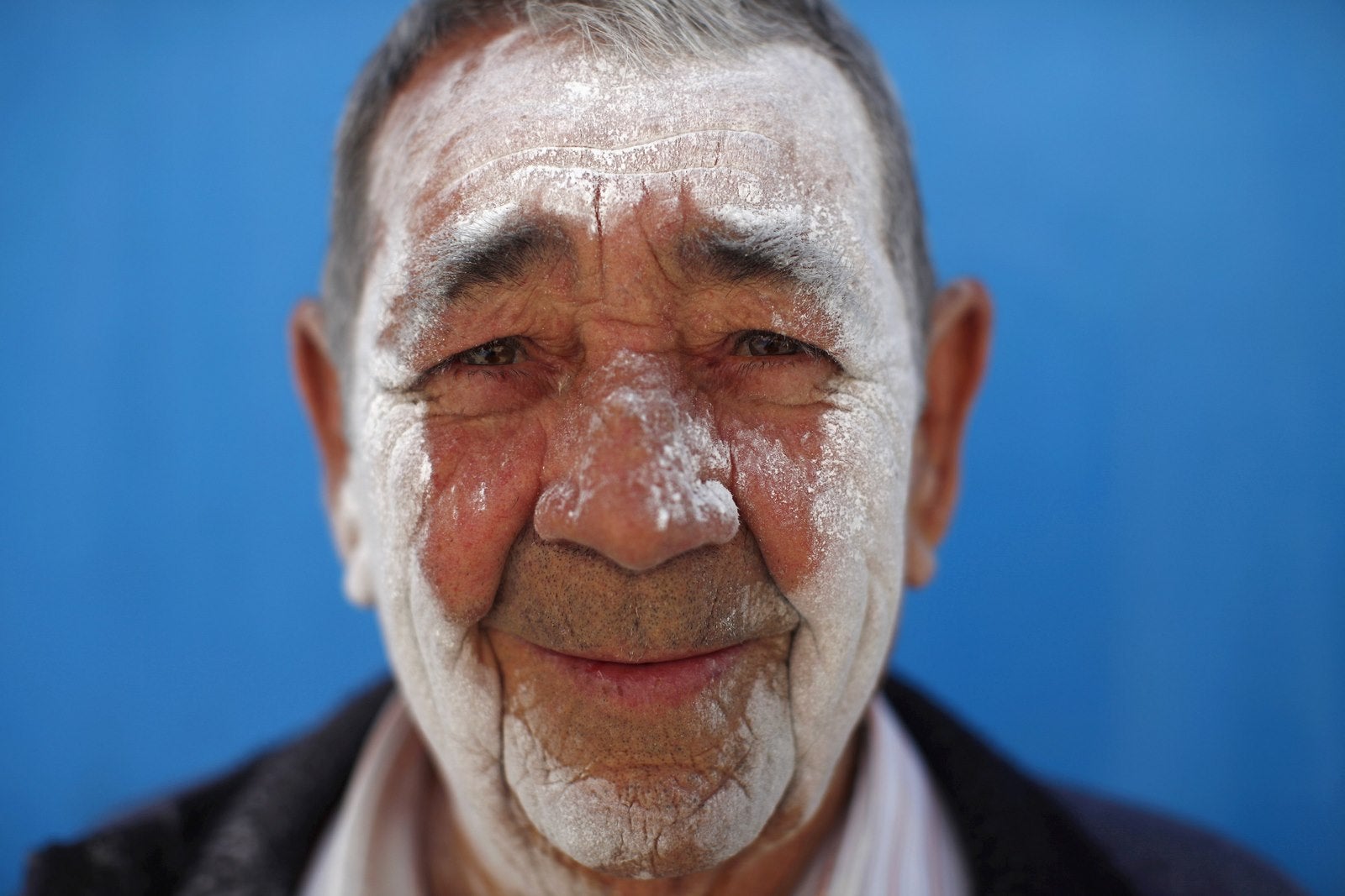 Un hombre con su rostro cubierto de polvo de talco posa para una foto durante el festival "El Día de los Polvos" (día del polvo) en Tolox, cerca de Málaga.