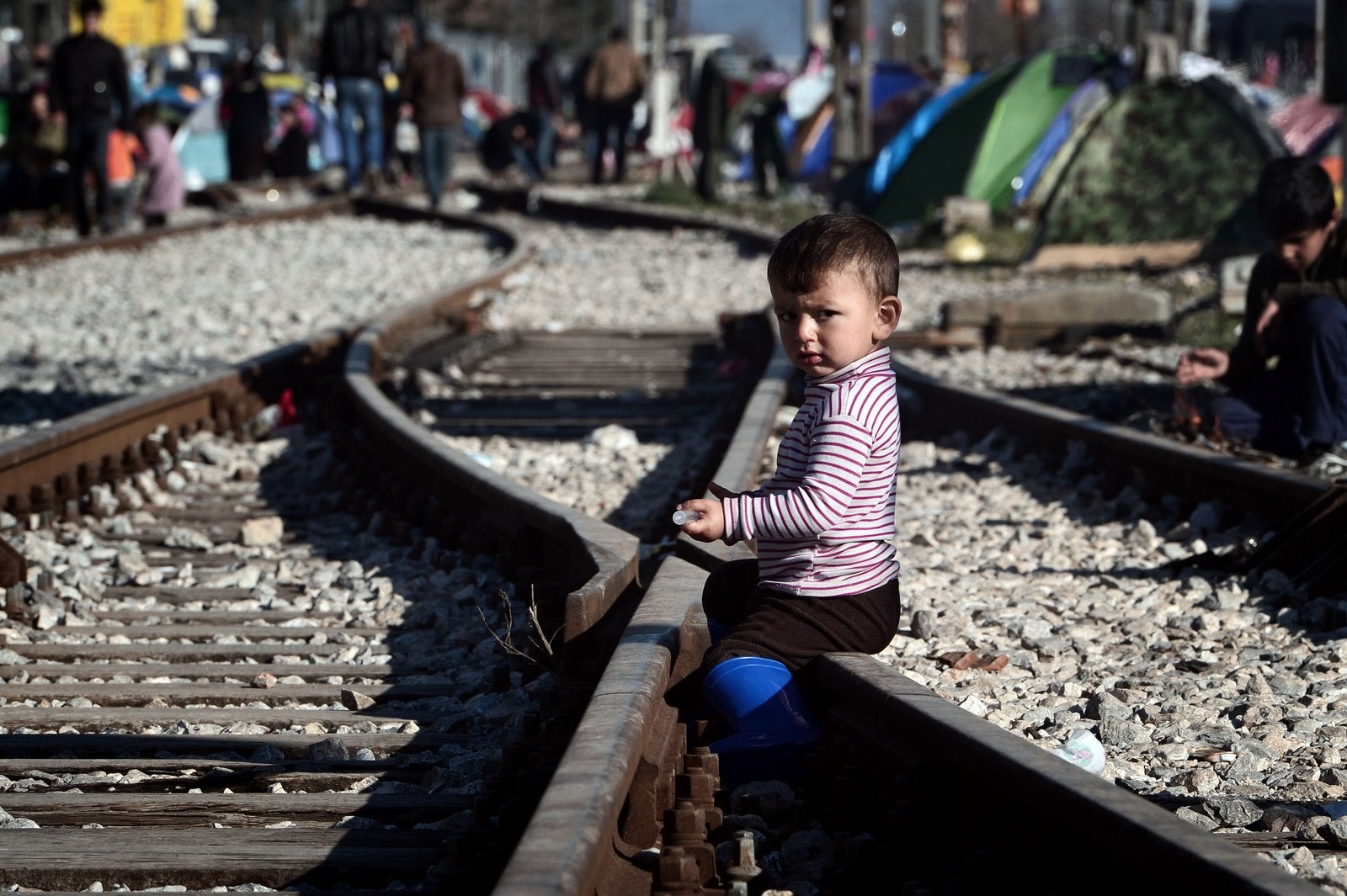 Un muchacho mira sentado en las vías del tren en el campo provisional de hacinamiento en la frontera entre Grecia y Macedonia.