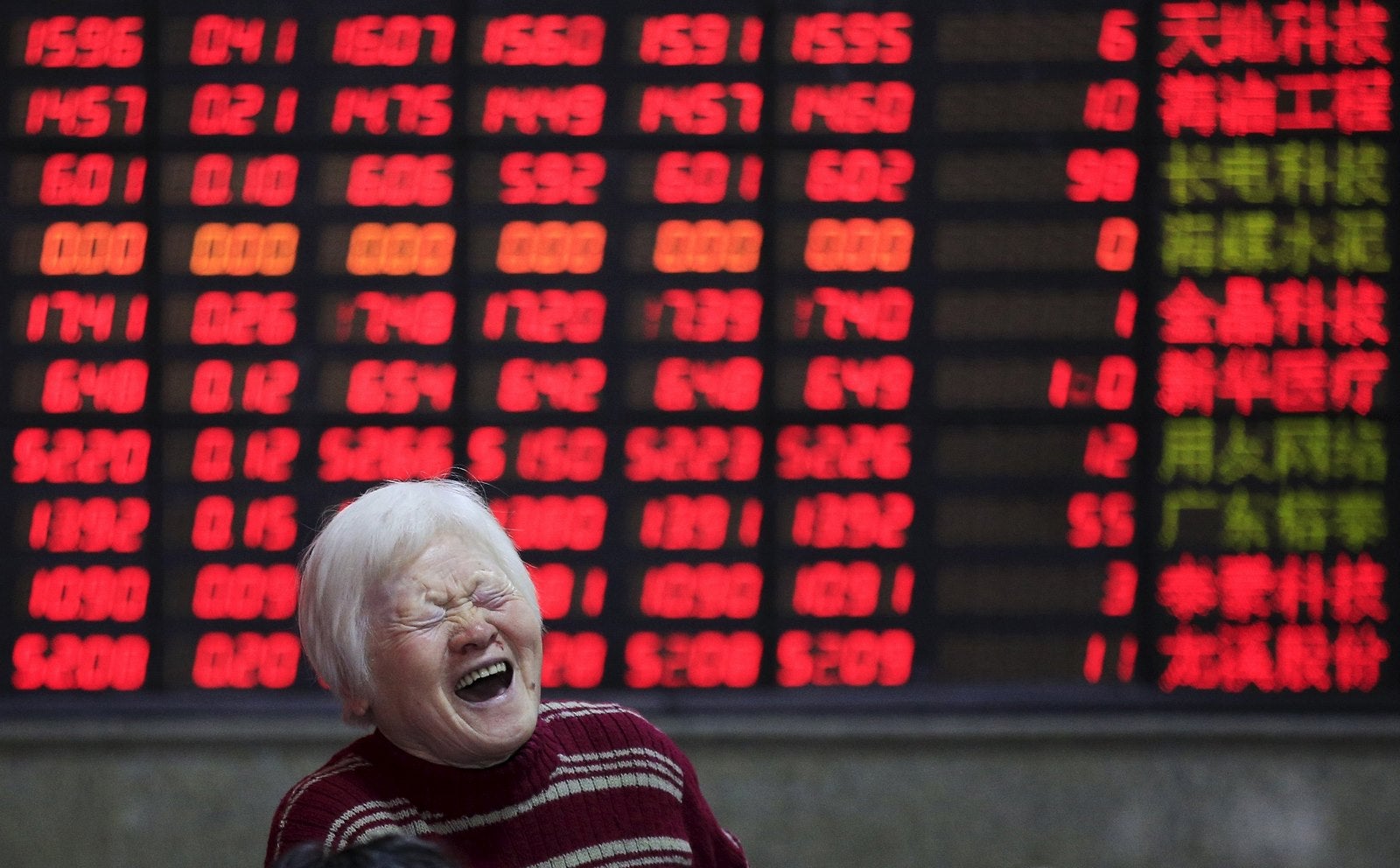 Un inversor reacciona frente a un tablero electrónico que muestra información de acciones de bolsa en Shanghai, China.