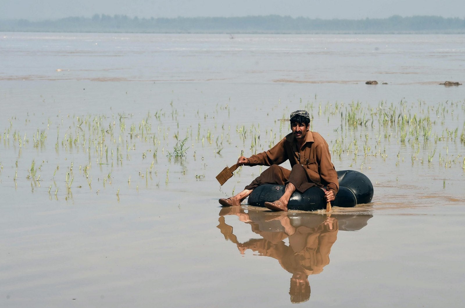 Un Pakistaní se encuentra en una cámara de aire en un área inundada tras fuertes lluvias en las afueras de Peshawar
