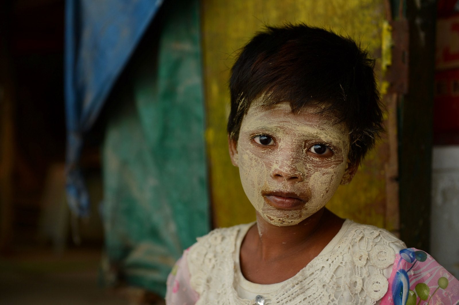 - Ocho años de edad, Myanmar Sable Moe, que significa flor de jazmín y de la lluvia, el uso de protección tradicional de sol de pasta cosmética mira desde una orilla del río en Yangon