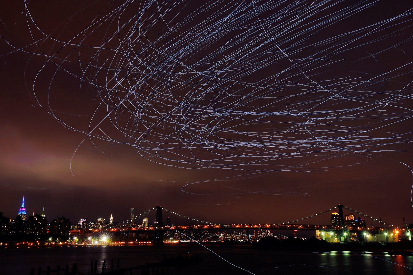 Las luces LED conectados a las palomas dejan estelas de luz en el cielo mientras vuelan como parte de la instalación de arte "Fly By Night" de Duke Riley por encima del barrio de Brooklyn de Nueva York, Estados Unidos