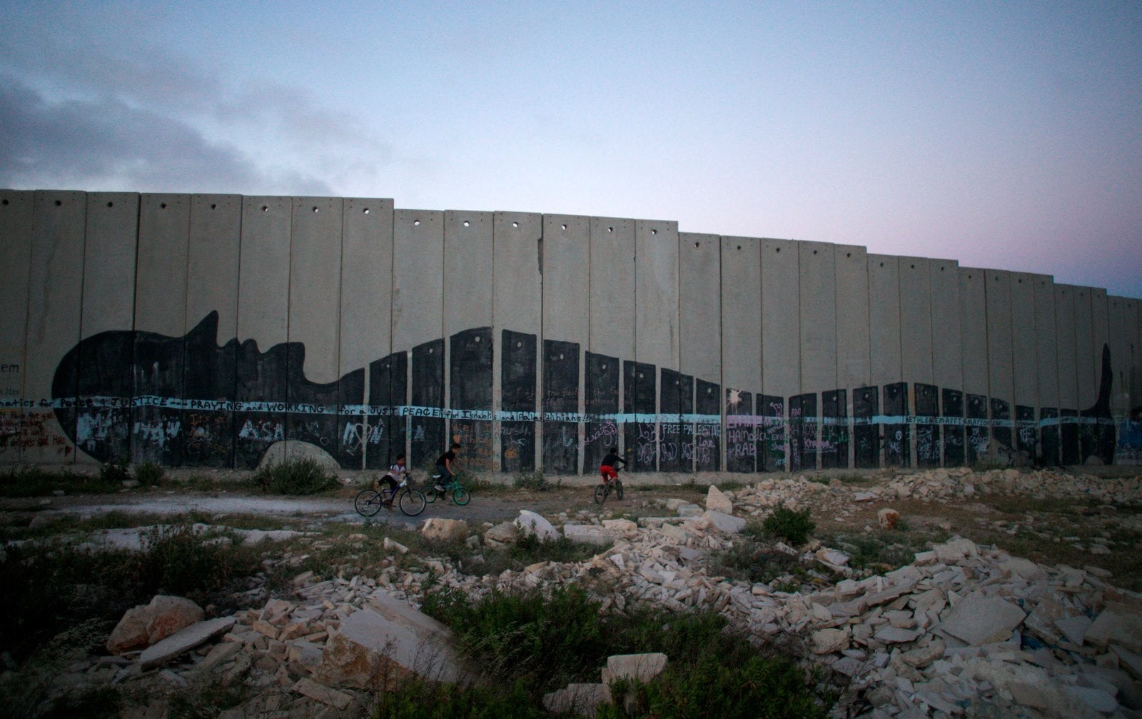 Muchachos palestinos pasean en bicicleta cerca de la pintada del controvertido muro israelí en la ciudad cisjordana de Belén.