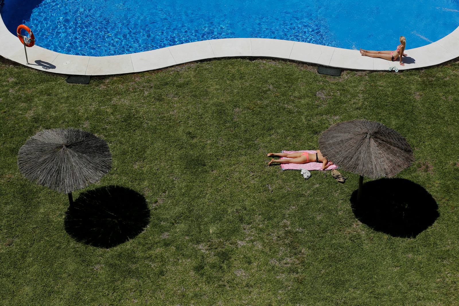 Mujeres tomando el sol en una piscina de Tomares.