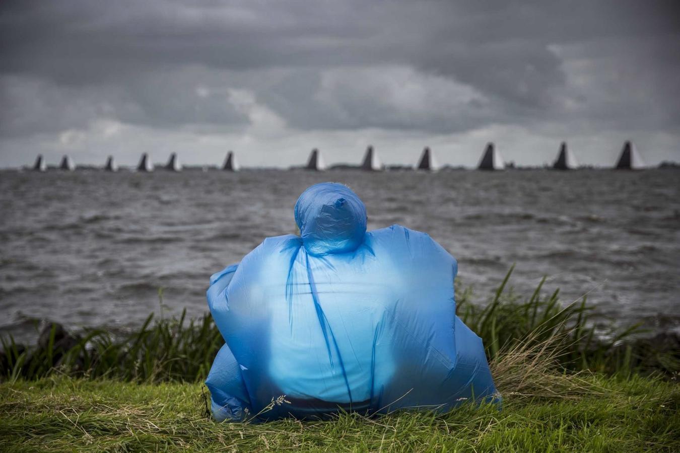 Una persona observa a los veleros que participan en la sexta edición de la competición de vela de Skutsjesilen, una tradicional regata con veleros de las ciudades que componen la región de Frisia.