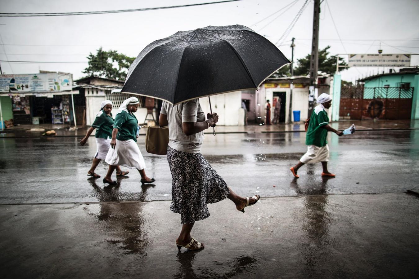 Una mujer lava un pie con el agua que fluye de una tubería cerca de la Iglesia de San Miguel en Libreville